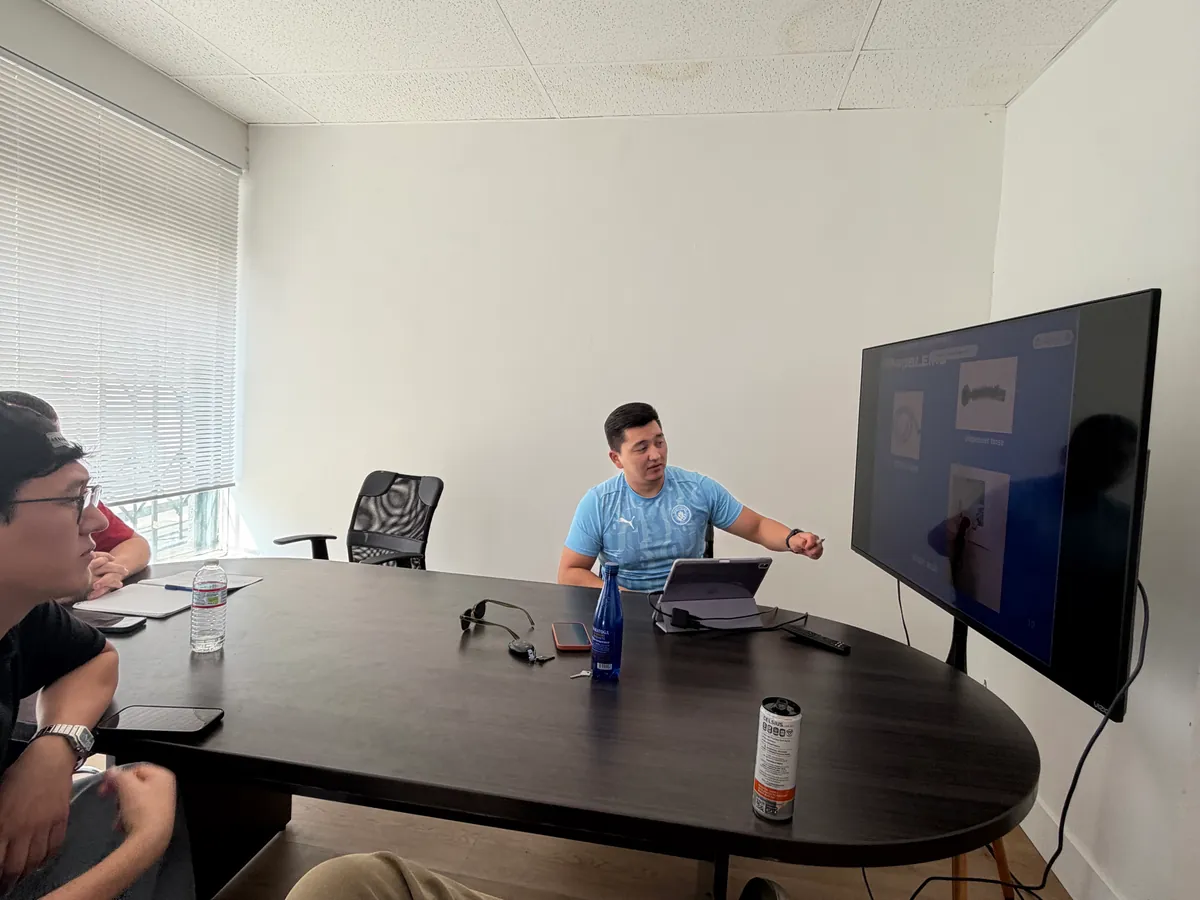 ApexPro trainer presenting an appliance diagram on a wall screen to apprentices seated around the table