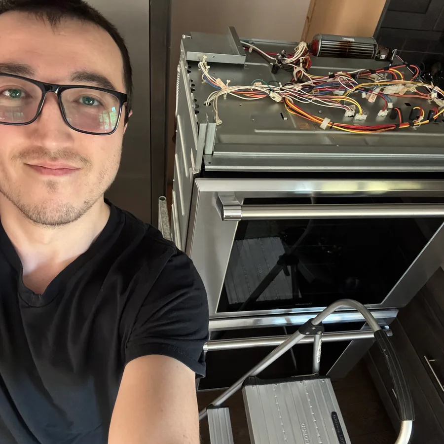Joe, ApexPro’s founder, beside a stainless double wall oven with the top panel off, exposing the wiring harness and blower motor