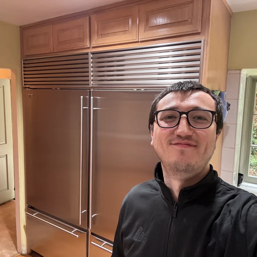 Joe, ApexPro’s founder, in front of a pair of stainless Sub-Zero built-in refrigerator and freezer columns under wood cabinetry